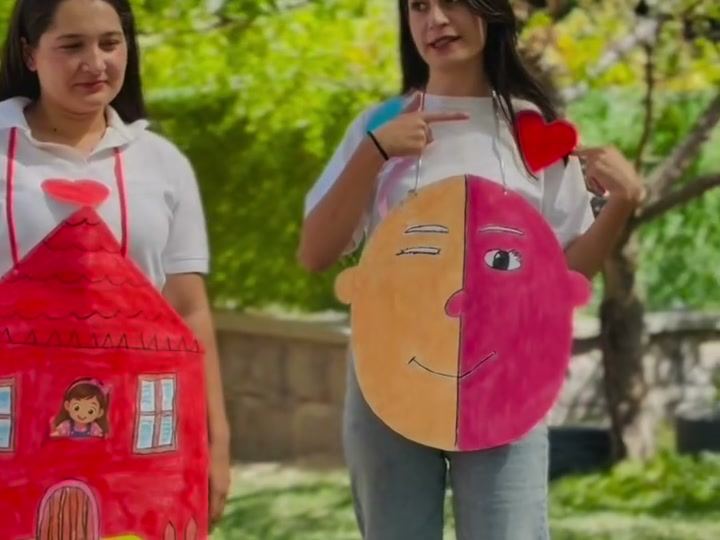 Ellerinde kâğıttan ev maketi tutan gülümseyen öğretmenler